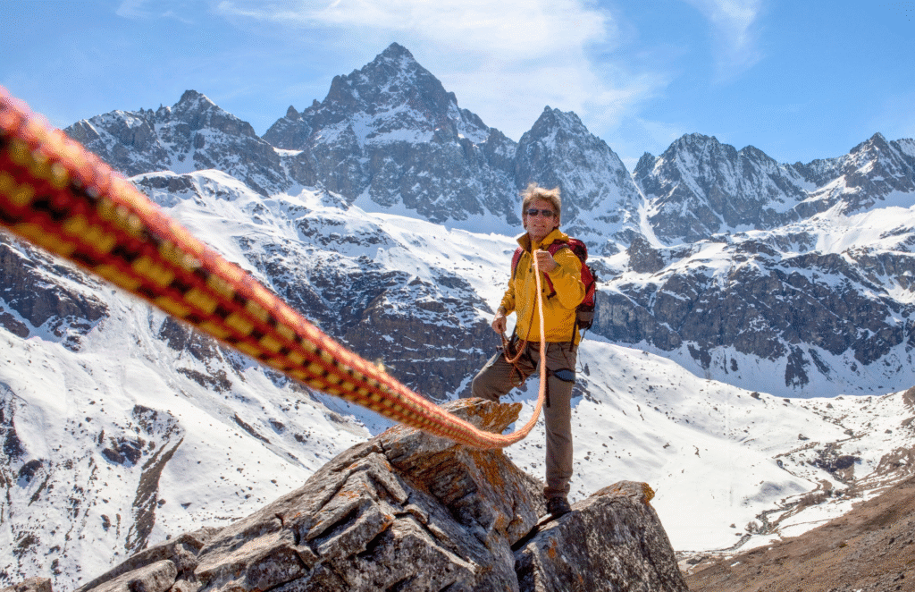 A man on top of a mountain grabbing a rope
