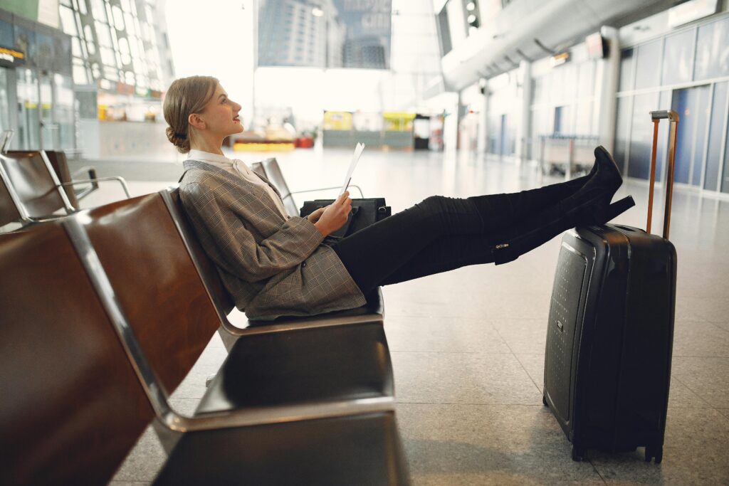 Woman Sitting On A Chair Inside An Airport - Budget Travel Tips
