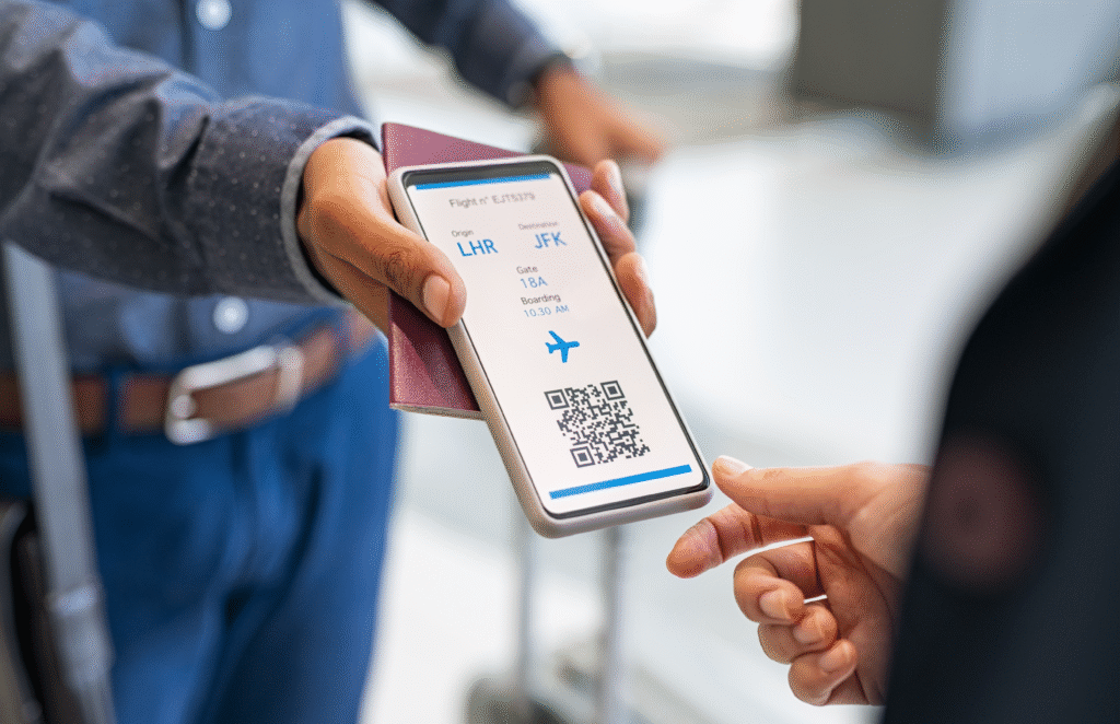 Close up hand of mixed race man showing electronic boarding pass to flight attendant on phone. Hostess checking electronic flight ticket at boarding gate. Airport check in counter and online air ticket.