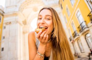 Cheap Travel Food Tips - A young women smiling while taking a bite of food
