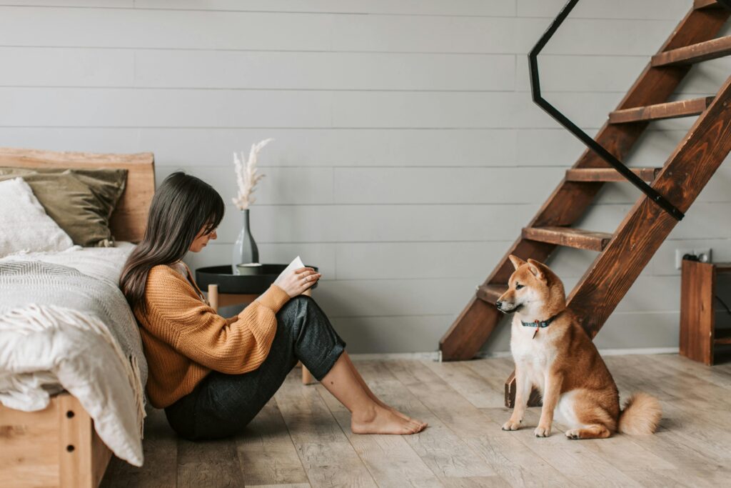 House-Sitting and Home Exchange - A Woman in Brown Sweater Sitting on the Wooden Floor