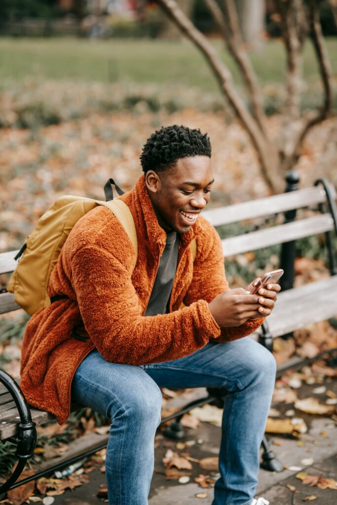 Track Cheap Flights - A young man sitting on a bench looking at his phone