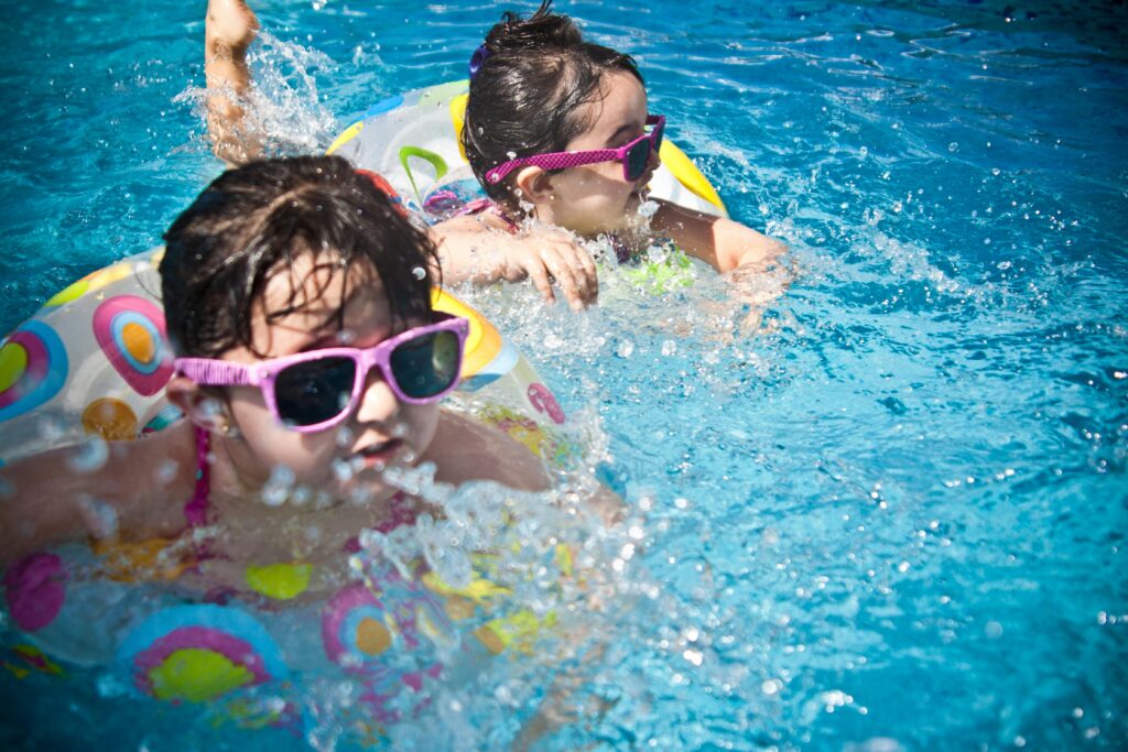 Kids wearing sunglasses and floaters playing on the pool