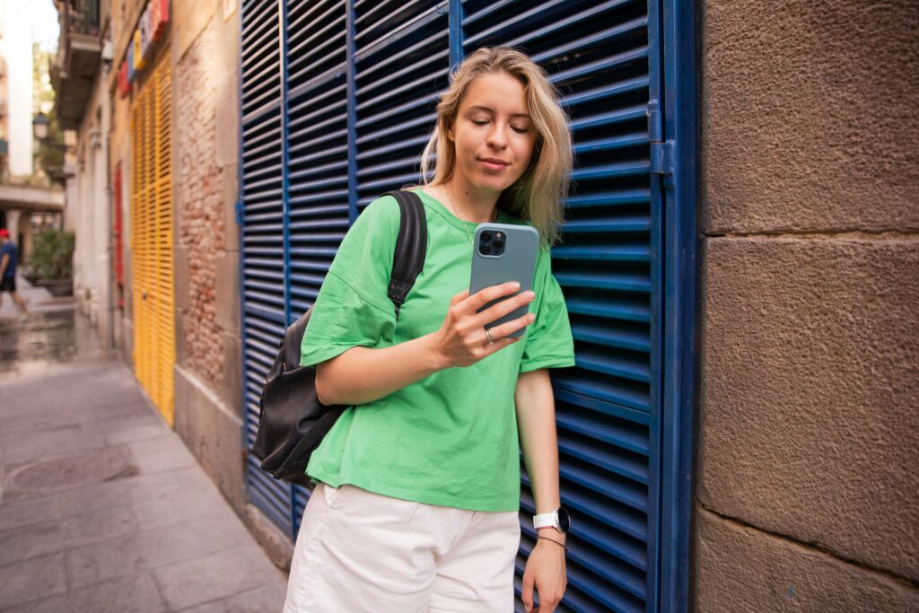 Traveletty - Affordable Accommodation - Female tourist looking at her phone while standing by the street