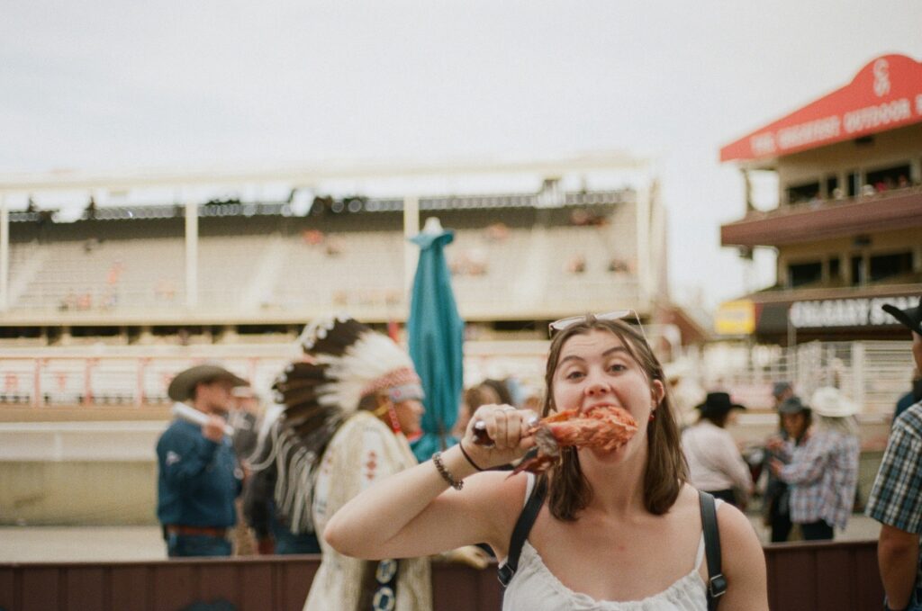 Cheap Travel Food Tips - Summary Image - A young woman eating street food in a foreign country she's travelling