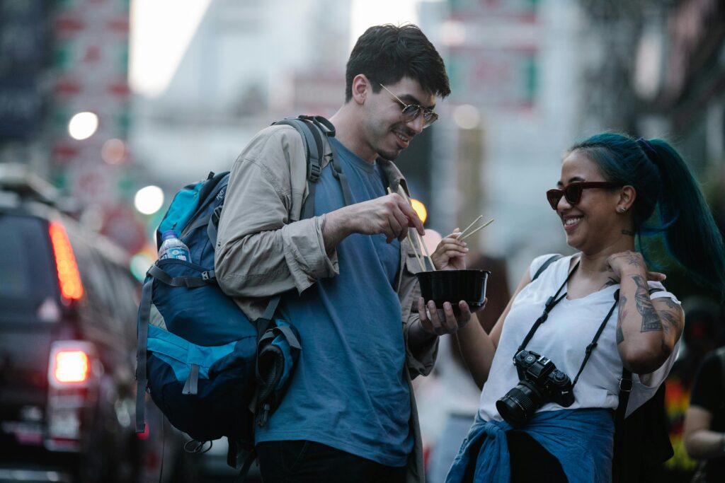 Cheap Travel Food Tips - Travel Hack - Two Tourists Eating a Chinese Food on the Street