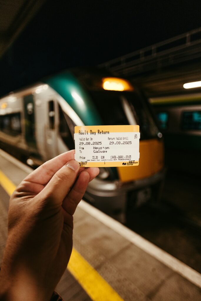 Traveletty - Public Transport for Travelers - Hand holding a train ticket with public transport train in the background