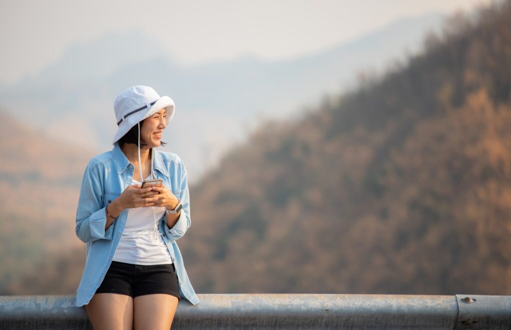 Traveletty - Best Free Travel Apps - A female tourist smiling while holding her phone