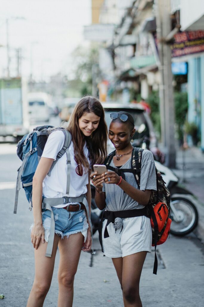 Traveletty - Best Free Travel Apps - Two female travelers looking at their mobile phones