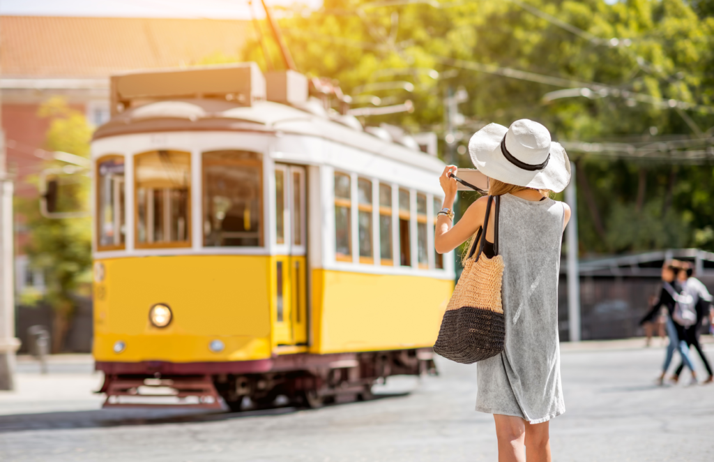 Budget Travel Transportation - Young woman tourist photographing famous
retro yellow tram traveling