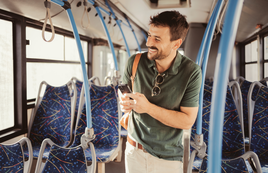 Traveletty - Budget Travel Transportation - A man using his smartphone in public transport