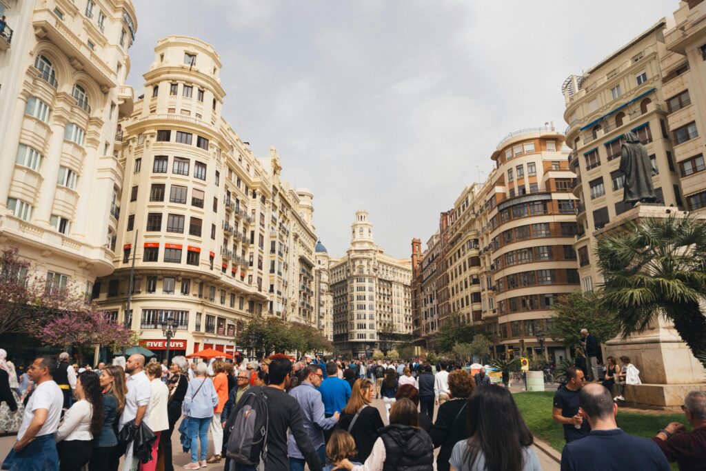 Traveletty - Free Travel Attractions - Tourists walking along the Modernisme Plaza of the City Hall of Valencia, Spain