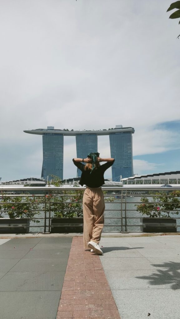 Traveletty - Free Travel Attractions - An image of a young female tourist looking the stunninv view of Marina Bay Sands from the Merlion View in Singapore