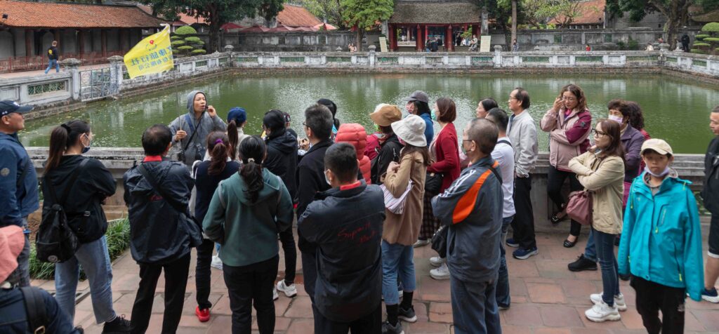 Traveletty - Free Walking Tours - A group of tourists listening to their tour guide during a free walking tour.