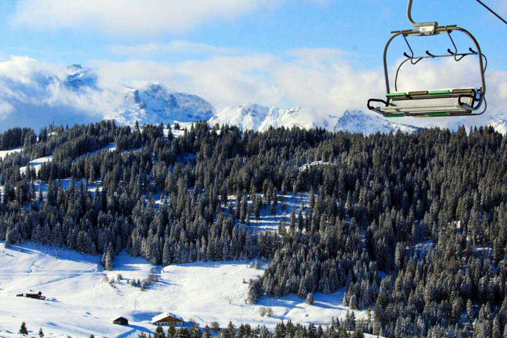 Traveletty - Ski Resorts - a cable car above snowy field under white and blue sky and powdery view of the mountains in a ski resort