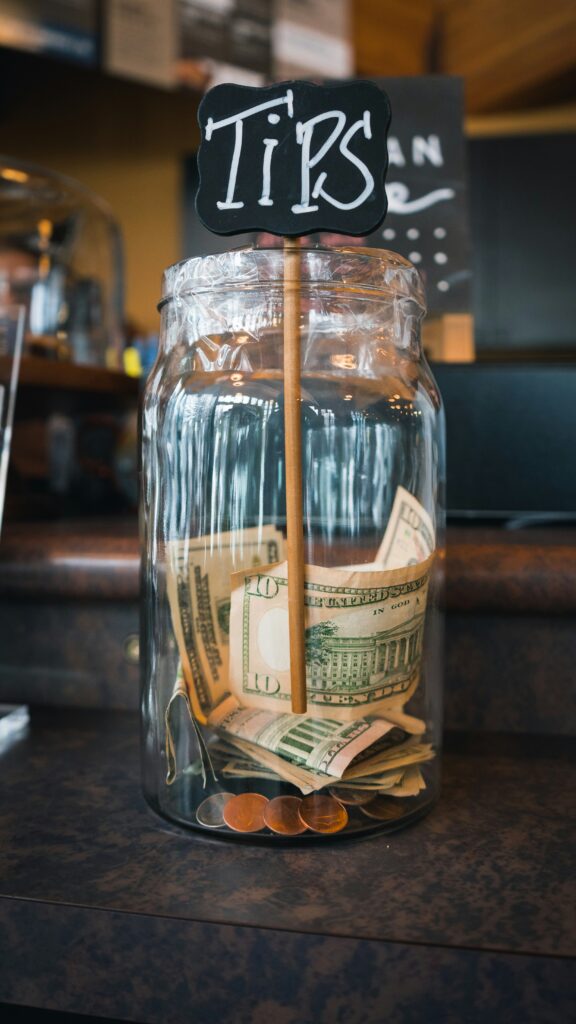 Traveletty - Travel Etiquette and Safety - A tip jar with dollar bill and coins inside
