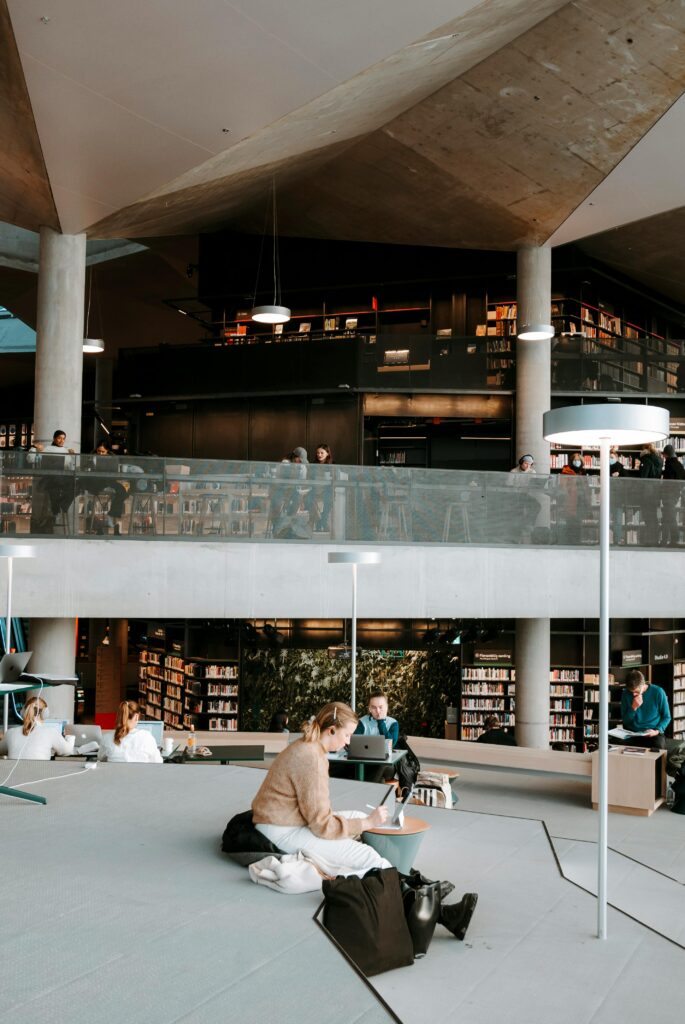 Traveletty - Visiting Libraries While Traveling - Digital nomads sitting and working inside a public library