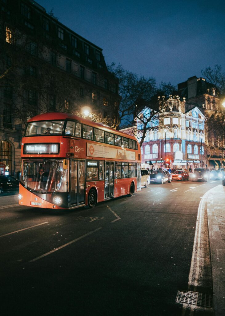 Traveletty - Budget Travel Transportation - A red double decker bus driving through the city at night
