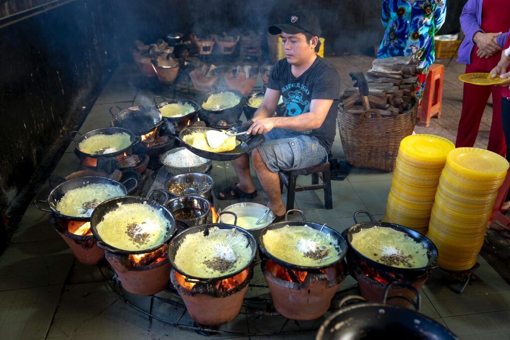 Traveletty - Budget Travel Food Tips - A male vendor cooking hot meals on the street