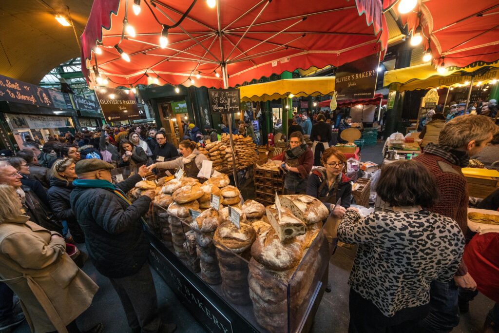 Traveletty - Budget Travel Benefits - A vibrant and busy market in London with lots of food displays and other goods.