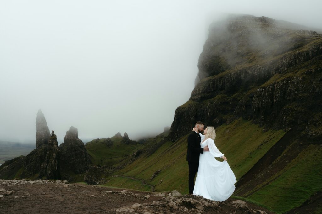 Traveletty - Romantic Travel Destination - couple embraces on a mountain for a wedding photoshoot in the Isle of Skye in United Kingdom