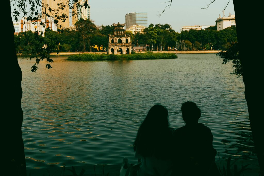 Traveletty - Romantic Travel Destination - silhouette of a couple sitting by the lake in Hanoi, Vietnam