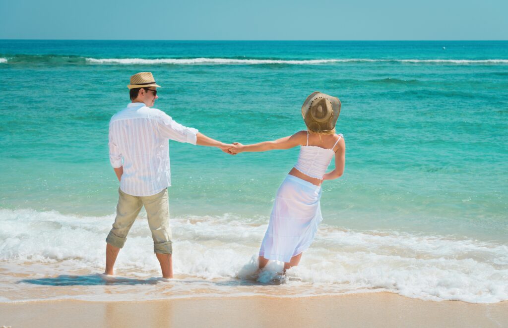 Traveletty - Romantic Travel Destinations - couple wearing the same color white outfit at the beach 
